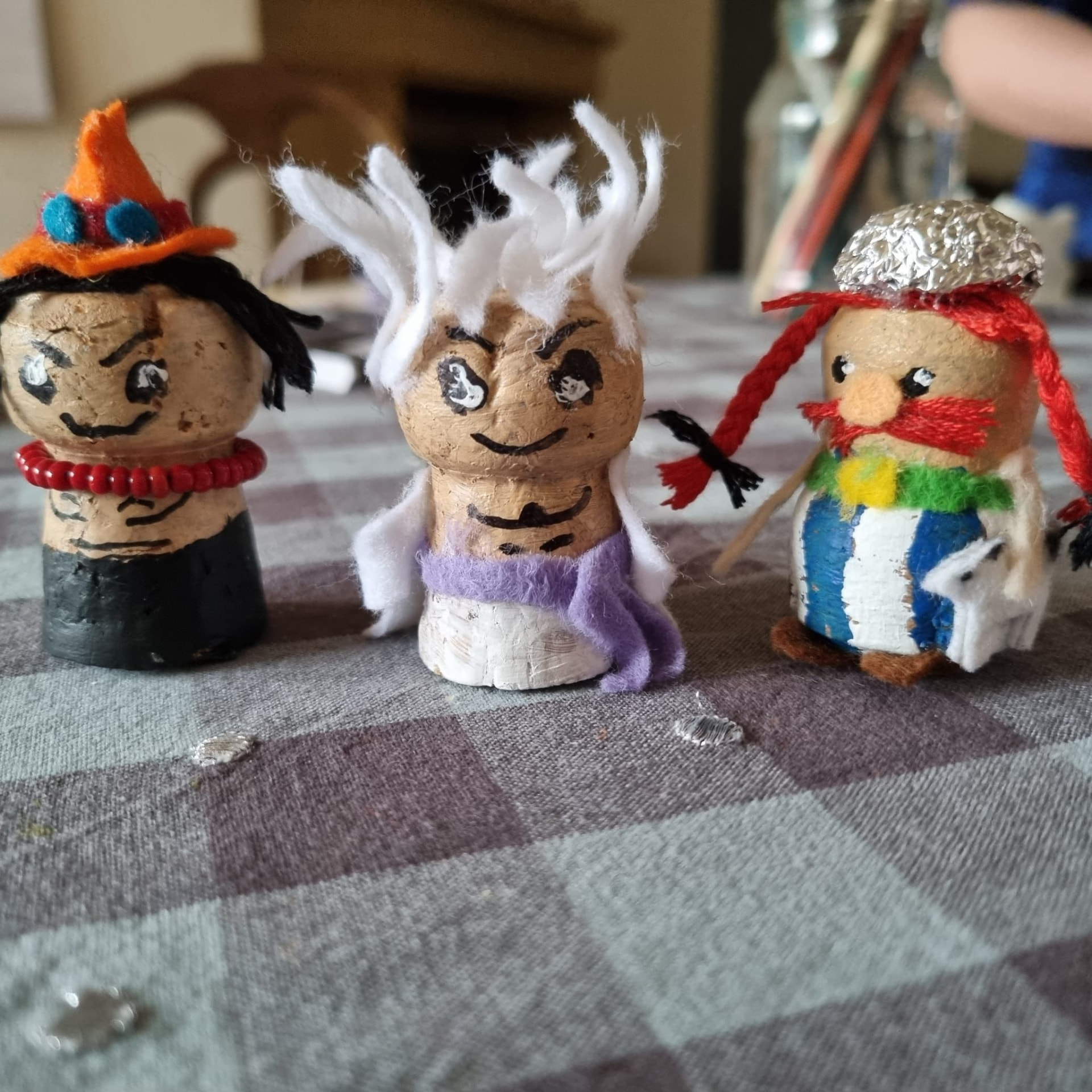 Drei bunte Tsapfie-Figuren auf einer karierten Tischdecke